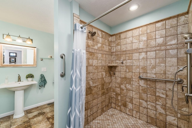 full bathroom with a stall shower, baseboards, and a textured ceiling