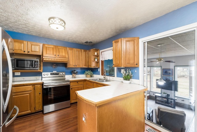 kitchen featuring tile countertops, a peninsula, stainless steel appliances, and a sink