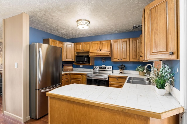 kitchen featuring stainless steel appliances, visible vents, a sink, wood finished floors, and a peninsula