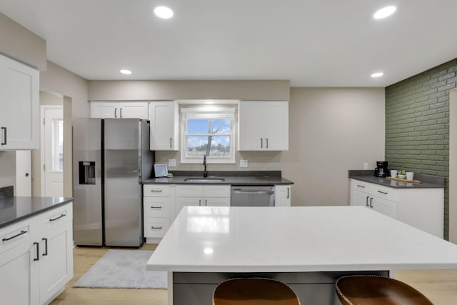 kitchen featuring stainless steel appliances, dark countertops, white cabinets, and a sink