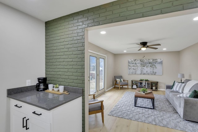 living area with light wood-style floors, ceiling fan, baseboards, and recessed lighting