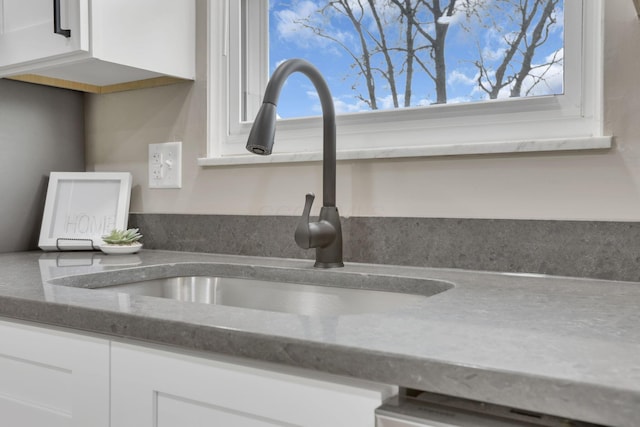 room details featuring dark stone counters, a sink, and white cabinets