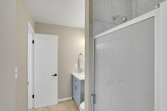 bathroom with toilet, a shower with door, wood finished floors, and vanity