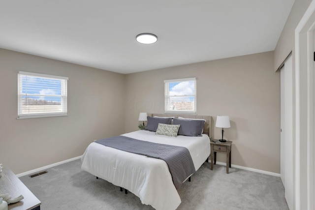 bedroom with light carpet, visible vents, and baseboards