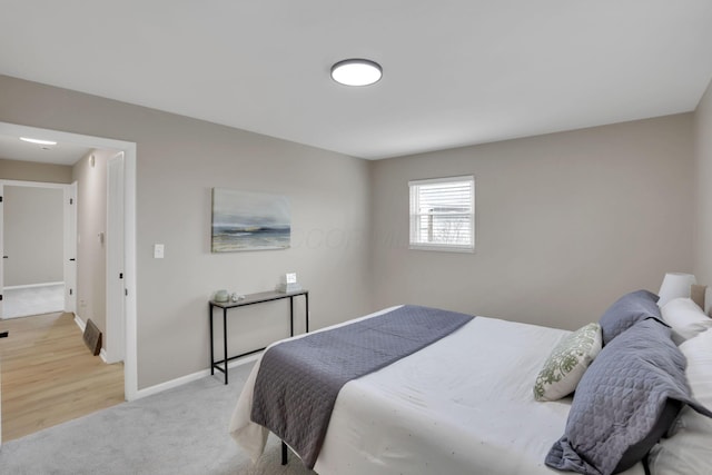 bedroom featuring light carpet and baseboards