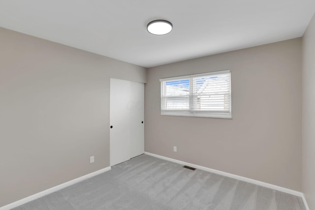 unfurnished room with baseboards, visible vents, and light colored carpet