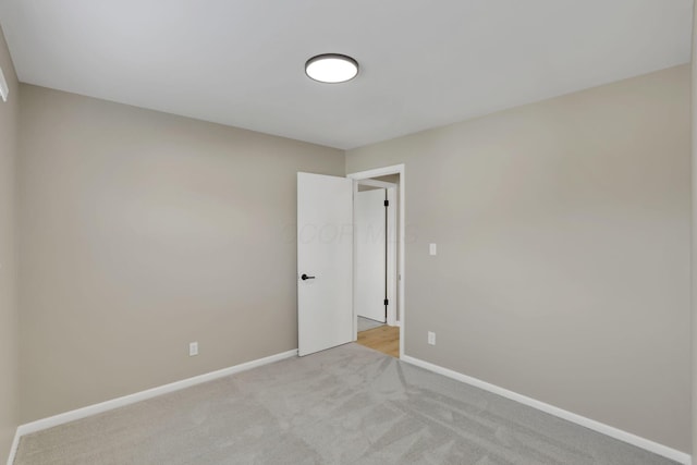 spare room featuring baseboards and light colored carpet