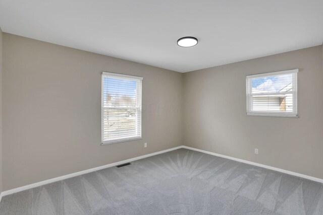 carpeted spare room featuring baseboards and visible vents