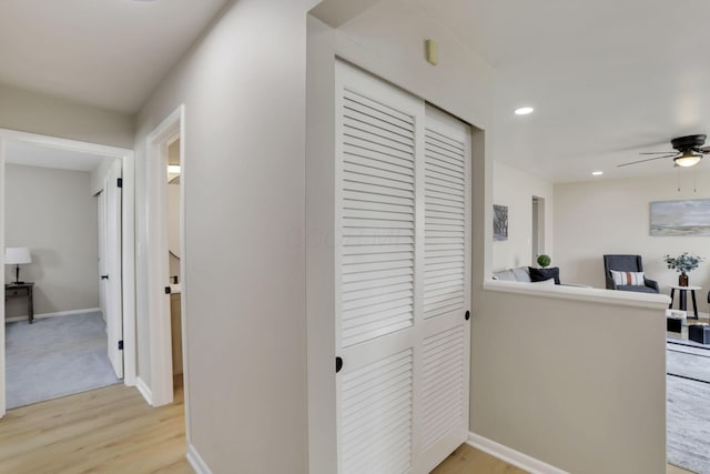 corridor featuring baseboards, light wood finished floors, and recessed lighting