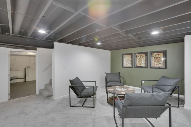 sitting room with stairs, baseboards, and light colored carpet