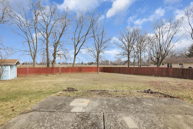 view of yard with a storage shed, a fenced backyard, and an outbuilding