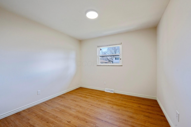 empty room featuring visible vents, light wood-style flooring, and baseboards