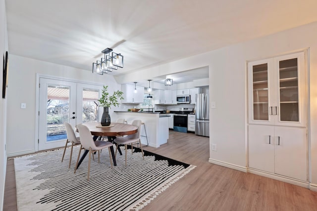 dining space with french doors, light wood-style flooring, and baseboards