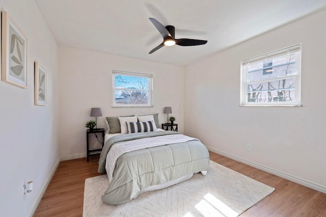 bedroom with multiple windows, baseboards, and wood finished floors