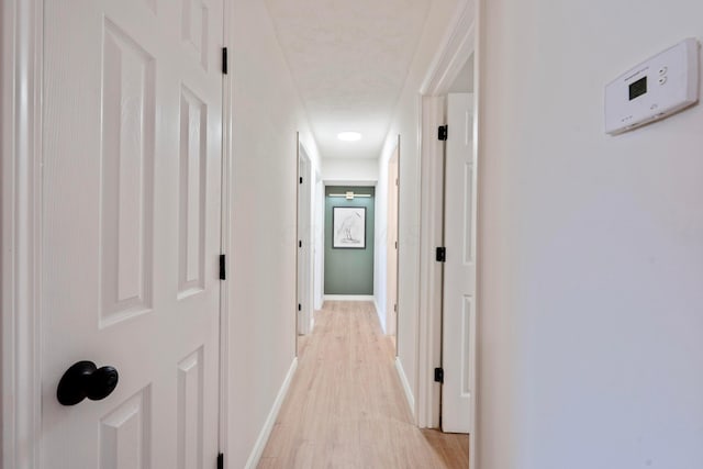 corridor featuring baseboards and light wood-style floors