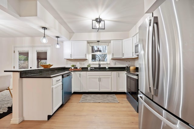 kitchen featuring french doors, light wood finished floors, stainless steel appliances, a sink, and a peninsula