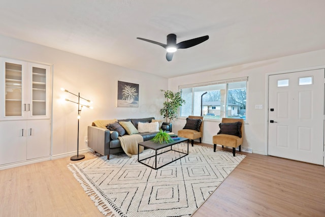 living area featuring light wood finished floors, baseboards, and a ceiling fan