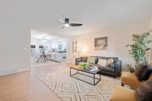 living area with baseboards, light wood finished floors, visible vents, and a ceiling fan