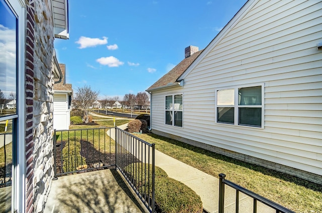 view of home's exterior with a shingled roof, a lawn, and a chimney