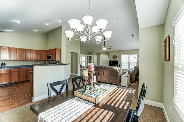 dining room featuring high vaulted ceiling, baseboards, and ceiling fan with notable chandelier