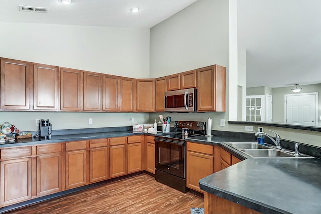 kitchen featuring dark countertops, visible vents, stainless steel microwave, electric range, and a sink