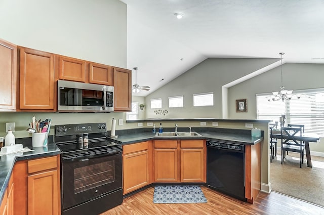 kitchen featuring dark countertops, brown cabinets, a peninsula, black appliances, and a sink