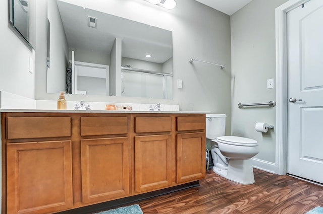 full bathroom with toilet, wood finished floors, visible vents, double vanity, and a shower with door