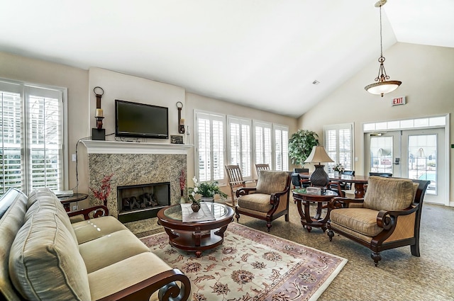 carpeted living area featuring a fireplace, high vaulted ceiling, and french doors