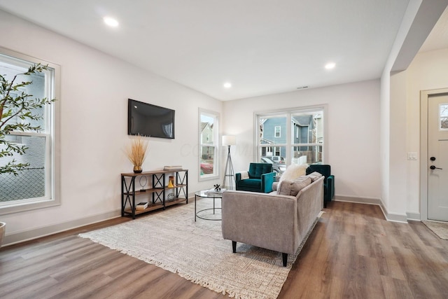 living area with baseboards, wood finished floors, and recessed lighting