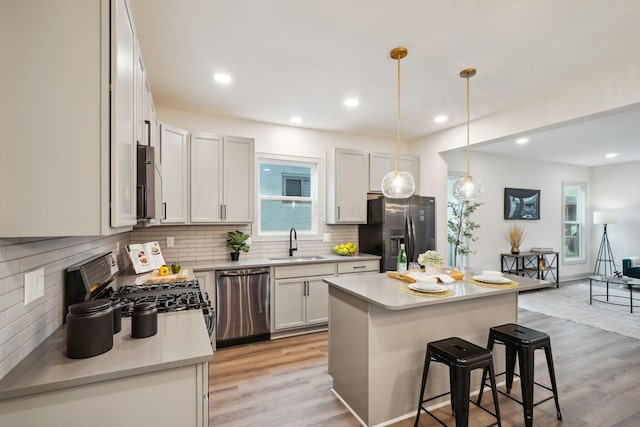 kitchen with light wood-style flooring, a breakfast bar, a sink, dishwasher, and black refrigerator with ice dispenser