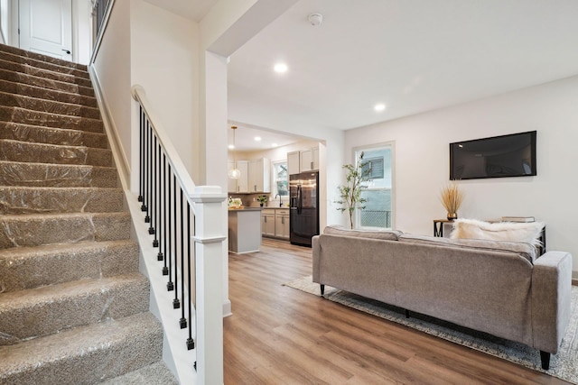 living area featuring light wood-style floors, recessed lighting, and stairway