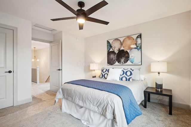 carpeted bedroom featuring attic access, baseboards, and a ceiling fan