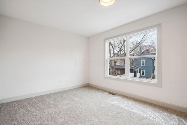 unfurnished room with carpet floors, visible vents, and baseboards