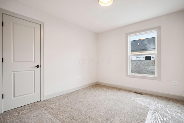 carpeted empty room with visible vents and baseboards