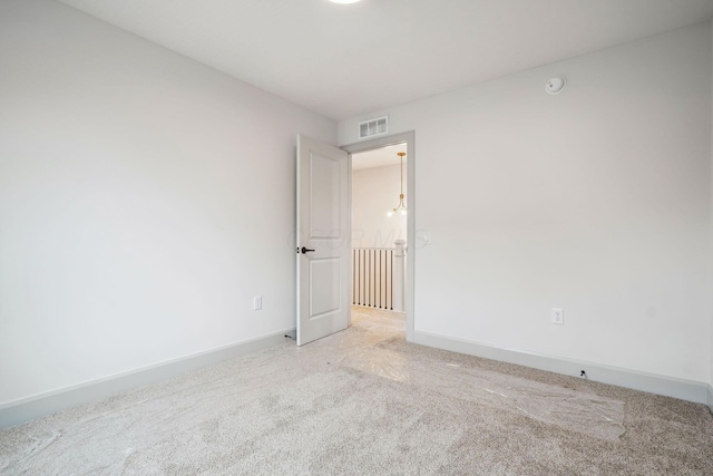 spare room featuring baseboards, visible vents, and light colored carpet