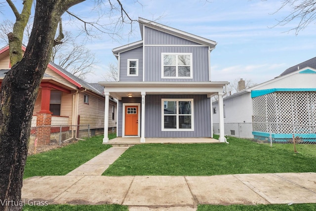 view of front of home featuring board and batten siding, covered porch, fence, and a front lawn