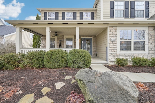 view of exterior entry featuring stone siding and covered porch