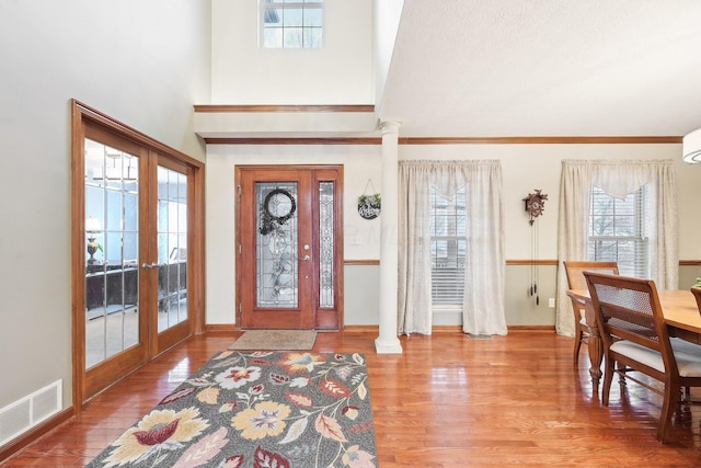 foyer featuring french doors, wood finished floors, visible vents, and ornate columns