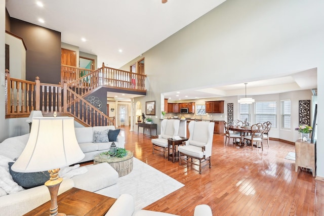 living area with stairs, light wood finished floors, recessed lighting, and baseboards