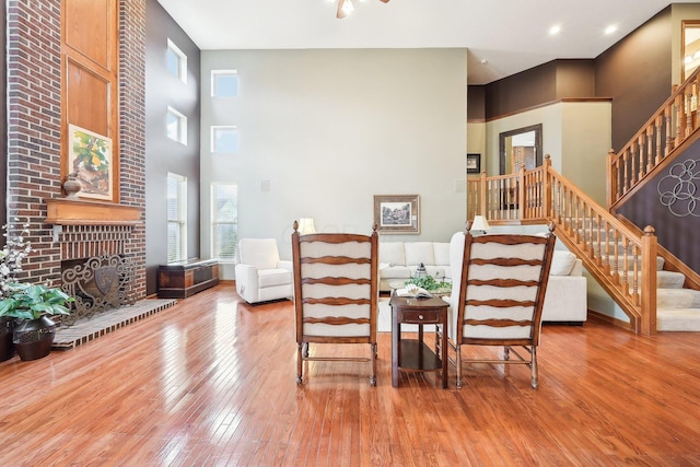 dining space with a high ceiling, hardwood / wood-style flooring, a fireplace, and stairway