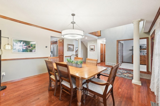 dining space with visible vents, wood finished floors, and decorative columns