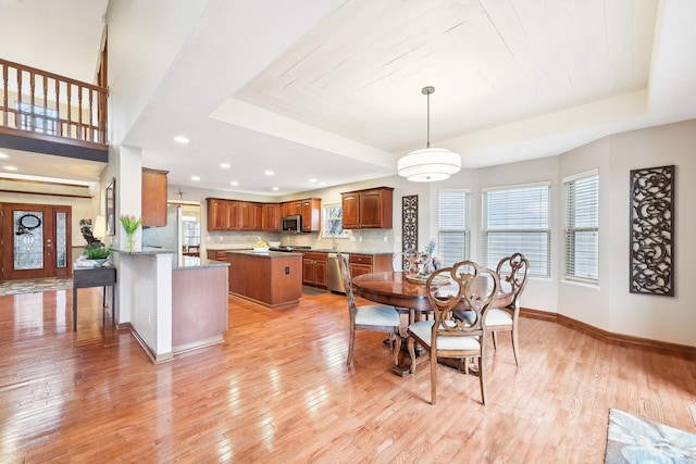 dining room with baseboards, a tray ceiling, recessed lighting, and light wood-style floors