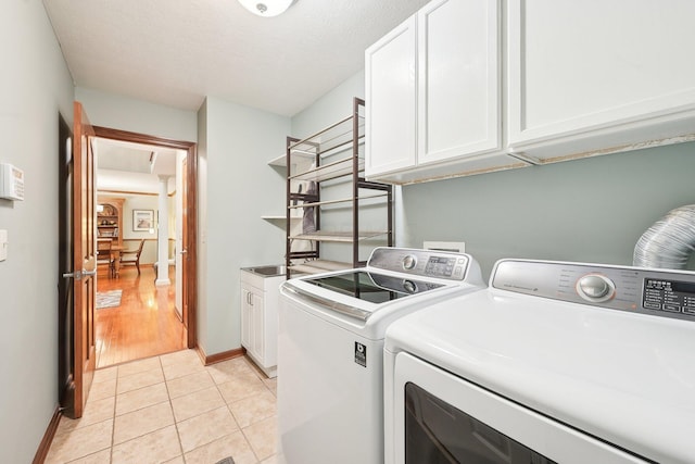 washroom featuring light tile patterned floors, a textured ceiling, baseboards, independent washer and dryer, and cabinet space