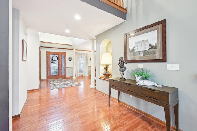 entryway featuring light wood-style floors, baseboards, and ornate columns