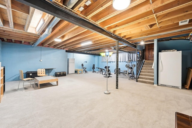 unfinished below grade area with visible vents, carpet floors, stairs, and freestanding refrigerator