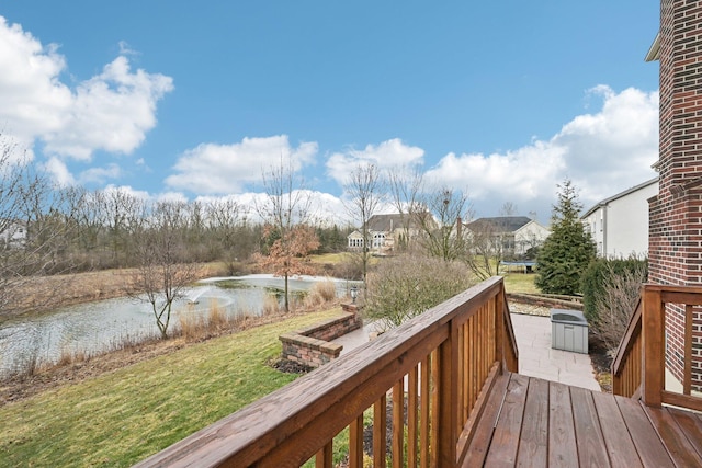 wooden deck with a water view and a lawn