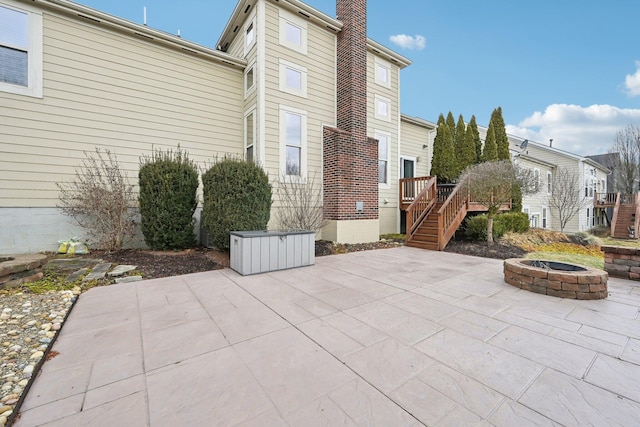 rear view of property featuring a chimney, a patio area, a fire pit, and stairs