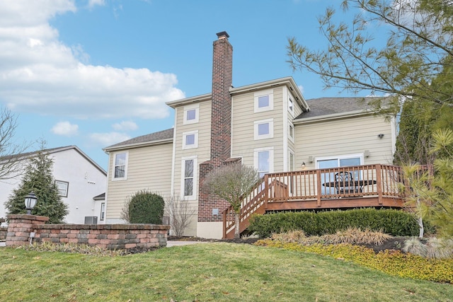 rear view of house with a deck, a lawn, and a chimney