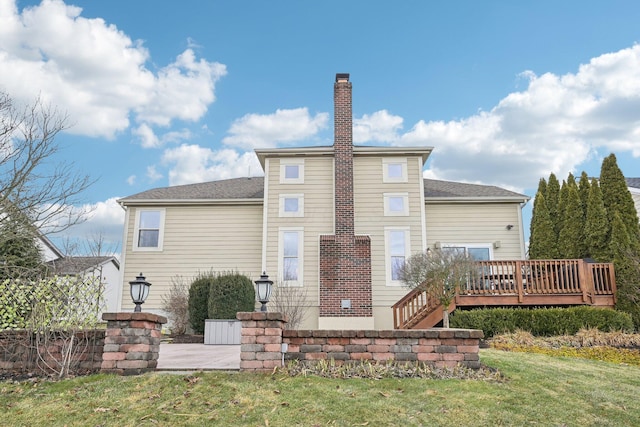 rear view of house with a chimney, a wooden deck, and a lawn