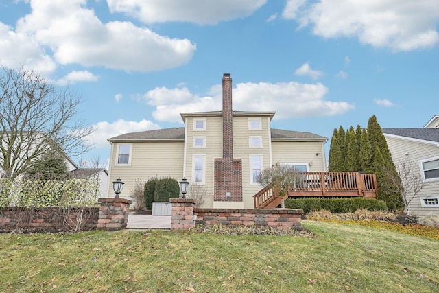 rear view of house with a chimney, a lawn, and a wooden deck